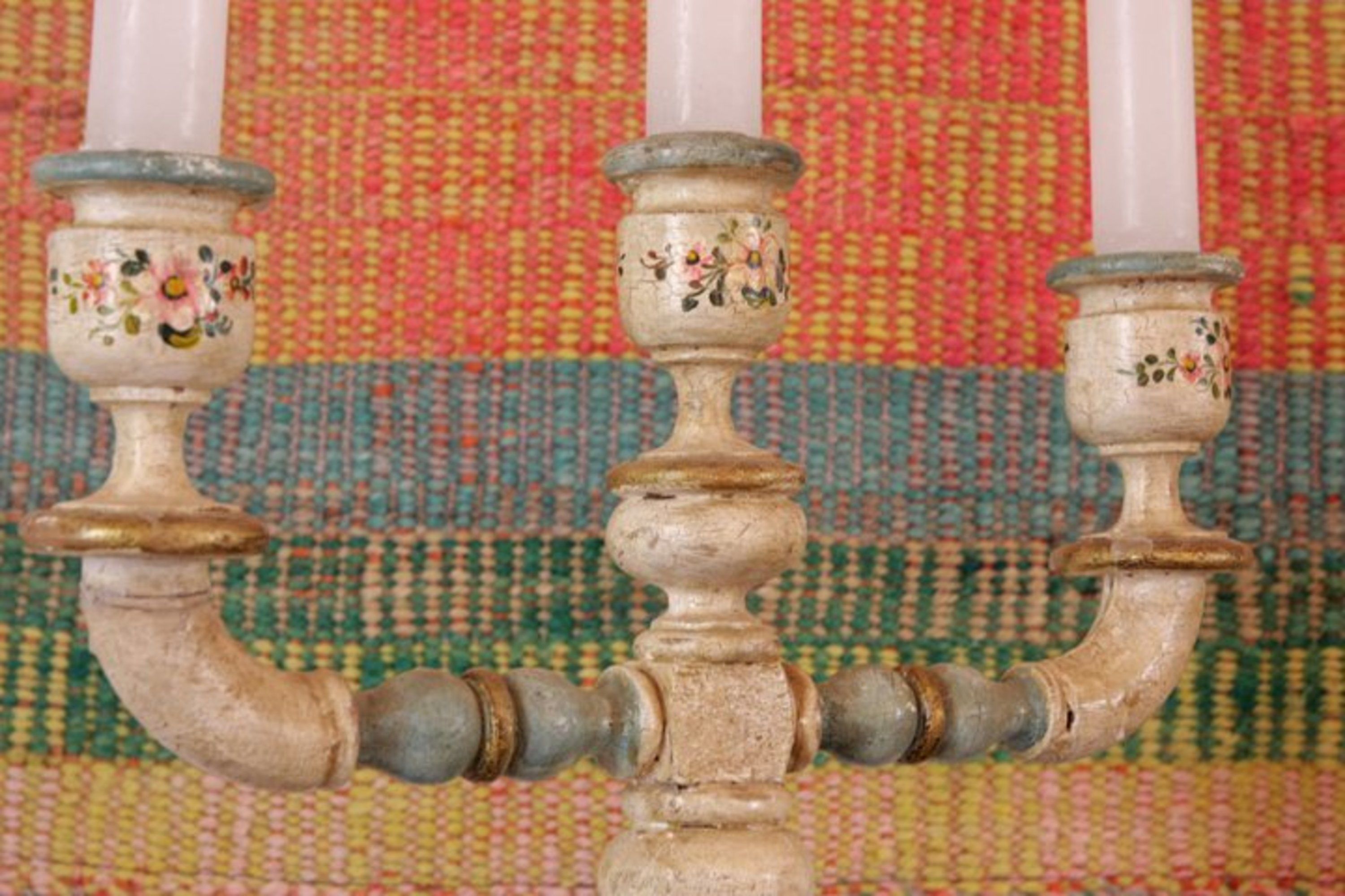 Primer plano de un adorno metálico con diseños florales, sobre un fondo de textil tejido y colorido.