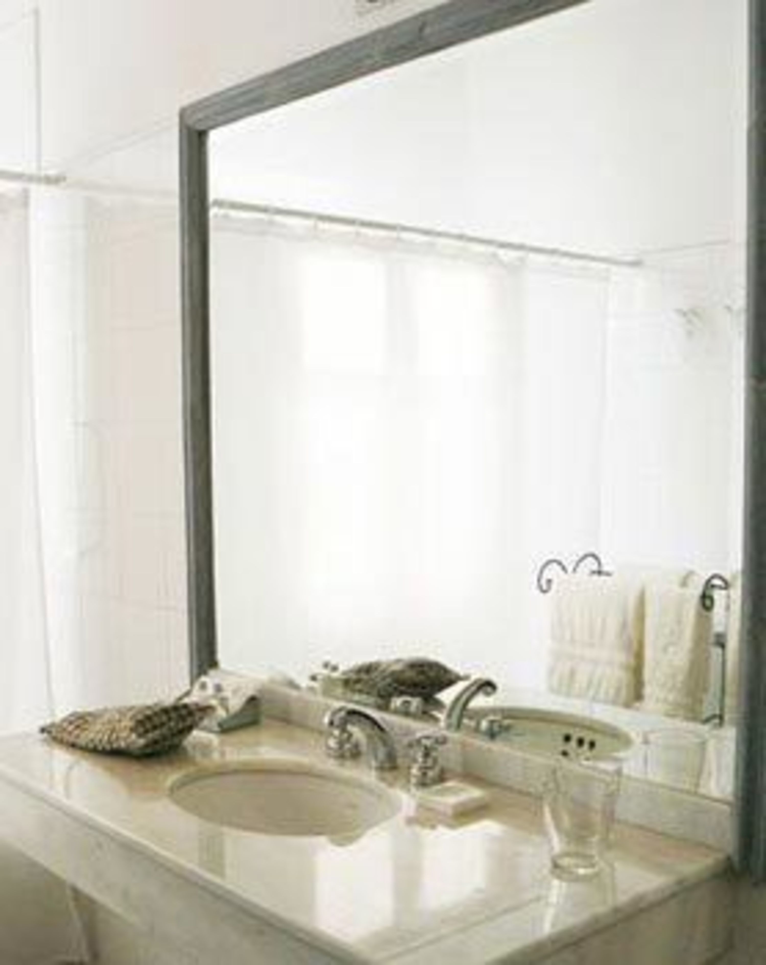 Ein Badezimmer mit einem großen Spiegel, einem Waschbecken und einem Handtuchhalter.