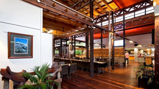 A spacious restaurant with high ceilings and wooden beams, featuring a bar area and multiple dining tables. - Noosa North Shore Retreat (Noosa North Shore)
