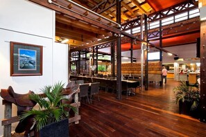 A spacious restaurant with high ceilings and wooden beams, featuring a bar area and multiple dining tables. - Noosa North Shore Retreat (Noosa North Shore)