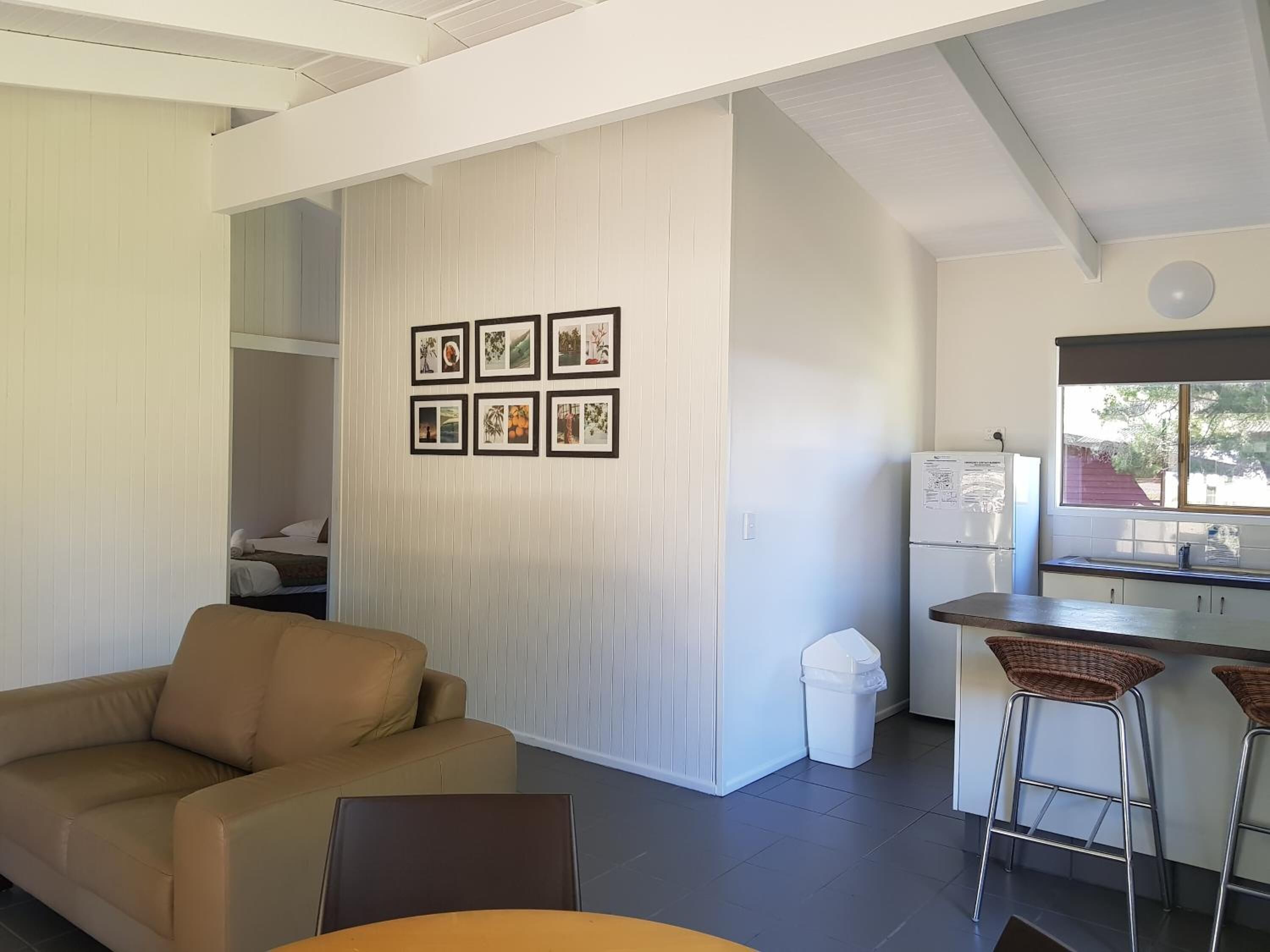 A modern kitchen with a refrigerator, a window, and a bar area with stools.