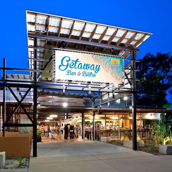 A modern bar and bistro with a prominent outdoor seating area and a large illuminated sign advertising the establishment. - Noosa North Shore Retreat (Noosa North Shore)