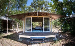 Una tienda de campaña individual con cama, una pequeña terraza y un toldo.