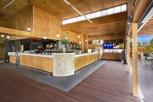 Zona de bar moderna con detalles de madera, una isla central y una pantalla de televisión.