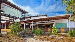 A restaurant with an outdoor patio, covered seating, and a landscaped garden area. - Noosa North Shore Retreat (Noosa North Shore)