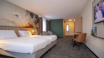 Habitación de hotel con una cama grande, un escritorio y una silla. Hay un cuadro en la pared y un televisor montado.