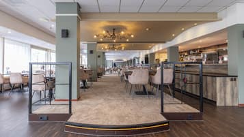 Een ruime hotellobby met een bar, zithoekjes en een centrale kroonluchter.