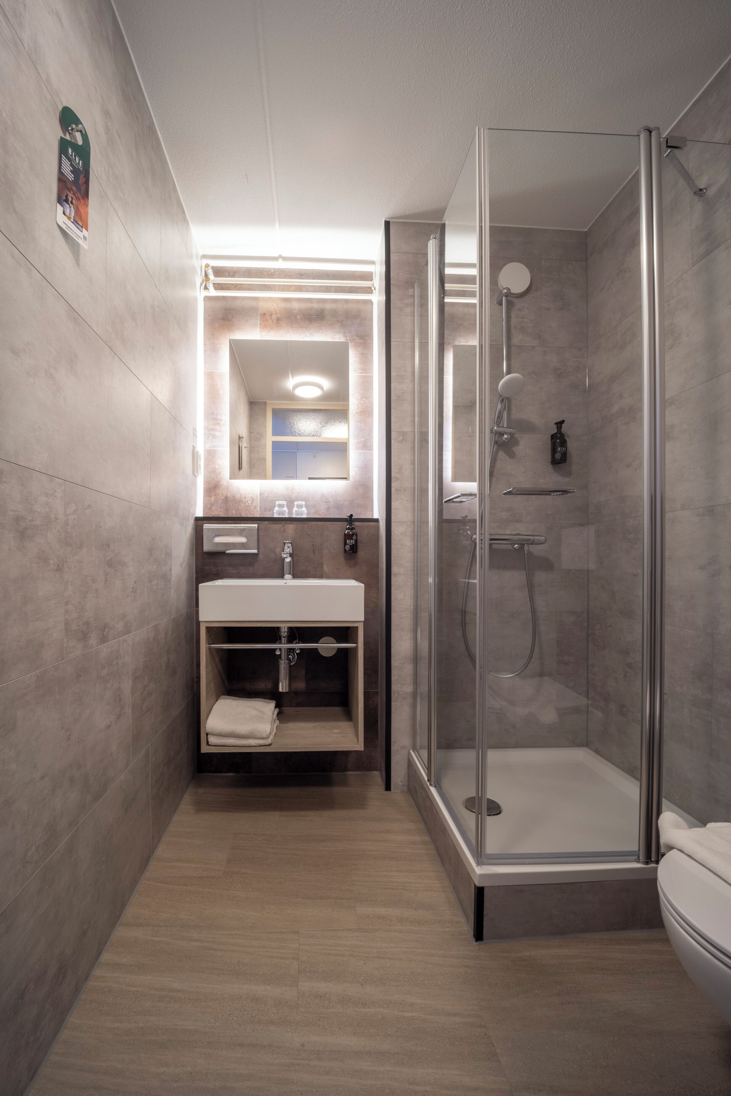 Un baño moderno con cabina de ducha de vidrio, lavamanos con espejo y toallero.