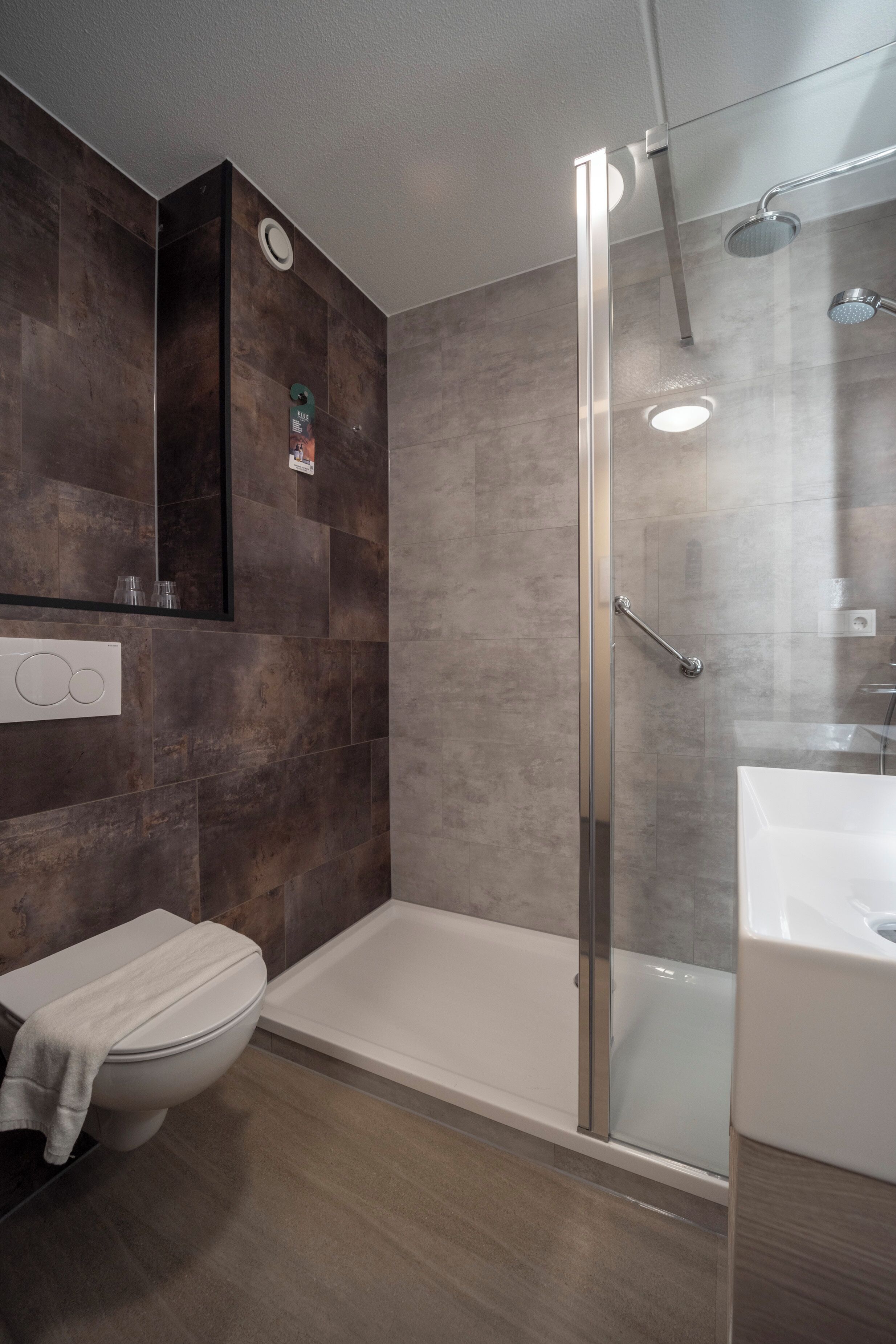Un baño moderno con ducha de vidrio, una bañera blanca y un inodoro.