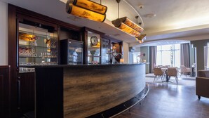 A bar area with a curved counter, shelves with glasses, and a seating area with chairs and a table.