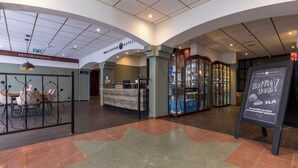 A hotel lobby with a reception desk, seating area, and a coffee bar.