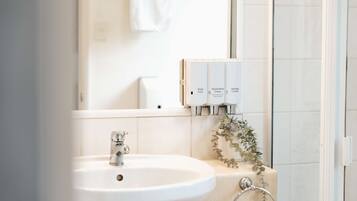 A bathroom with a white sink, a mirror, and a shower area.