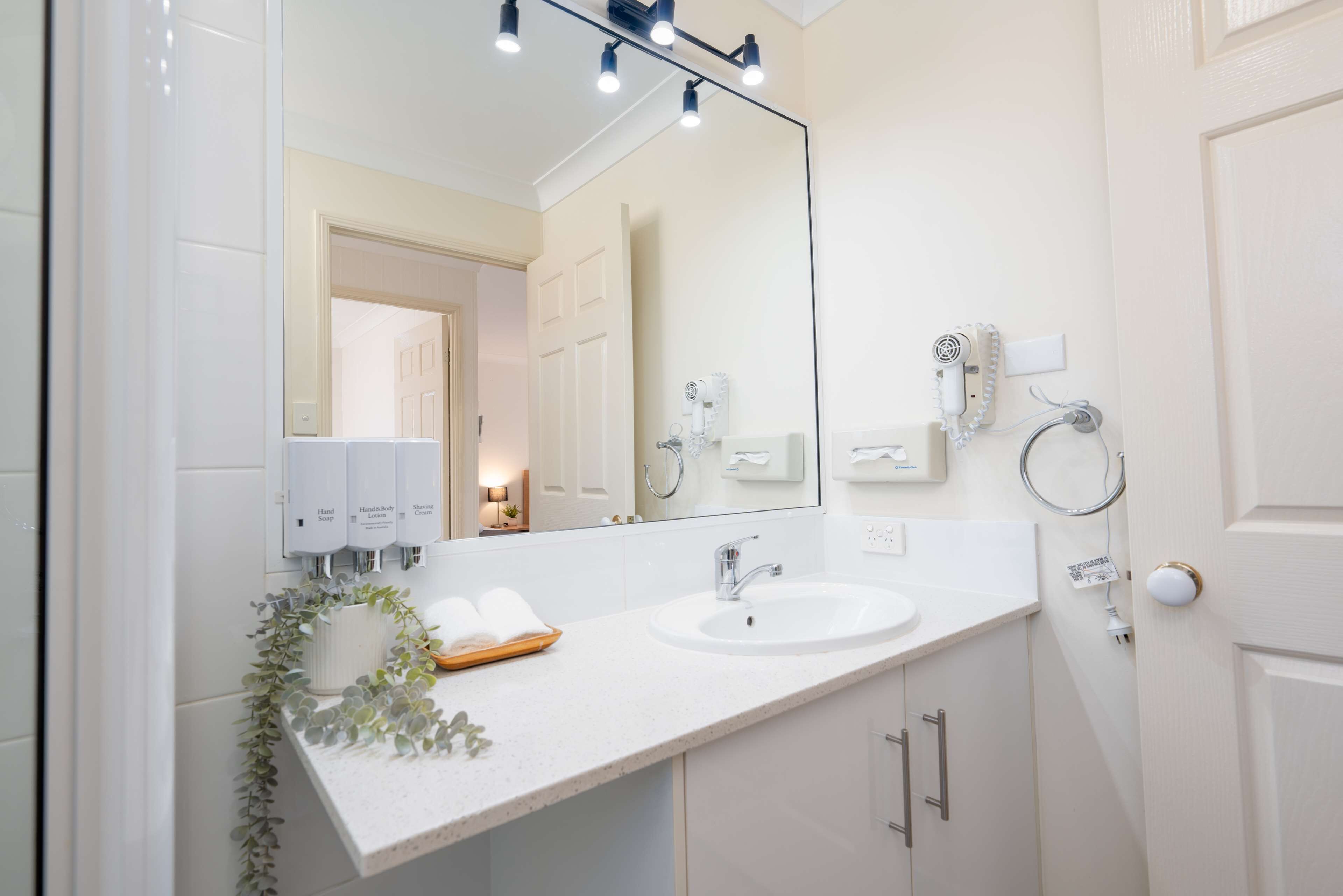Un baño moderno con un espejo grande, dos lavamanos y un perchero para toallas.