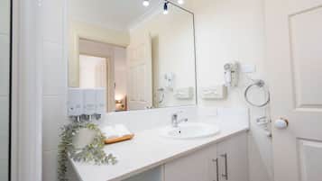 Un baño moderno con un espejo grande, dos lavamanos y un perchero para toallas.