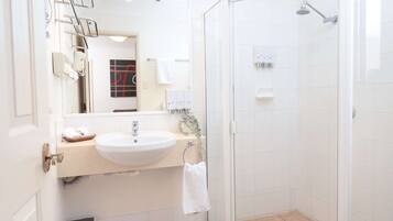 Une salle de bain moderne avec un lavabo blanc, un miroir et une douche en verre.