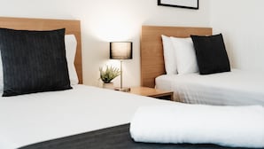 A hotel room with two beds, a nightstand with a lamp, and a potted plant. - Best Western Tuscany On Tor Motor Inn (Newtown)