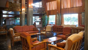 Un amplio hall con varias zonas de estar, chimenea y ventanas grandes con cortinas.
