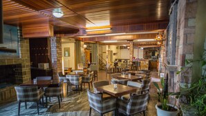 Un restaurante con pared de piedra, techo de madera y varias mesas y sillas.