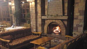 Un rincón acogedor con chimenea de piedra, asientos cómodos y una pequeña mesa.