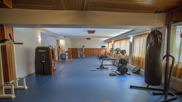 A gym with exercise equipment, a punching bag, and a bench. - Liberty Hotel (Mesolongi)