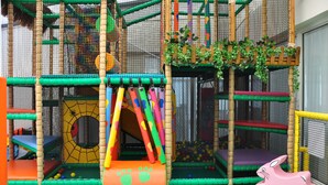 Zona de juegos infantiles con tobogán, red de escalada y piscina de pelotas.