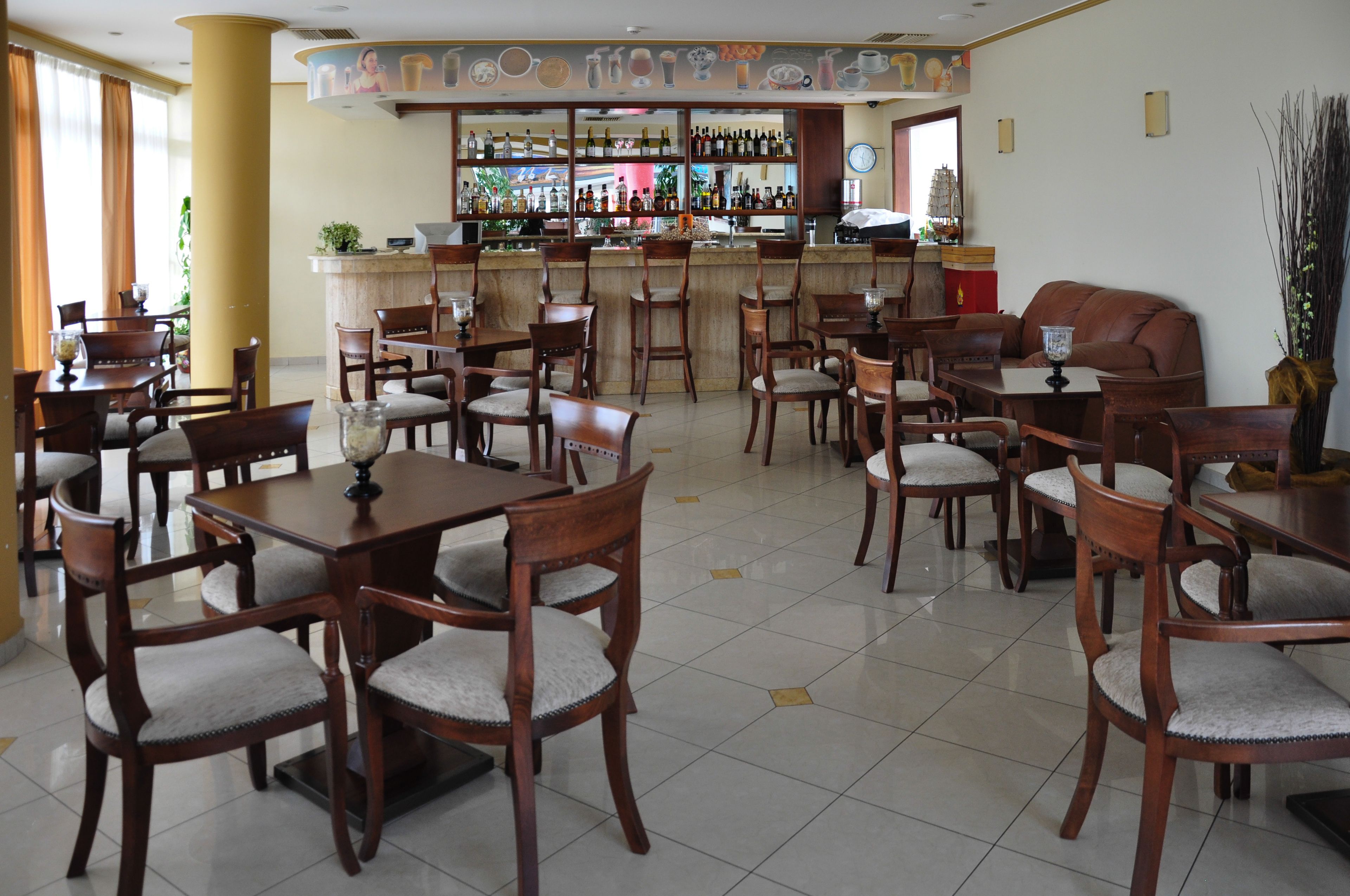 A restaurant with wooden tables and chairs, a bar area with bottles, and a ship model on the wall.