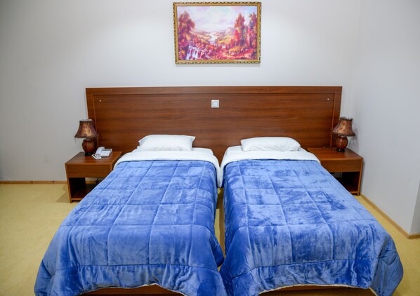 Una cama doble con cabecera de madera, dos mesitas de noche y un cuadro en la pared.