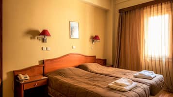 A hotel room with two beds, a wooden headboard, a bedside telephone, and two wall-mounted lamps.