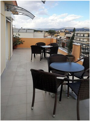 Una terraza en la azotea con mobiliario de mimbre, plantas en macetas y vistas a la ciudad.