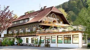 A traditional chalet-style hotel with a sloped roof, large windows, and a balcony area. - Gasthof zur Post (Ossiach)