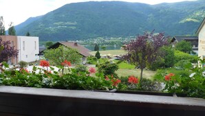 A view of a town with a mountain in the background, a building with a sign that reads "Pizza," and a balcony with flowers. - Gasthof zur Post (Ossiach)