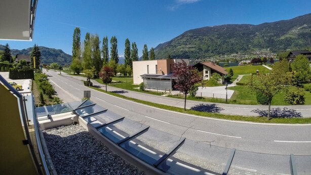 A residential street with houses, a clear sky, and mountains in the background. - Gasthof zur Post (Ossiach)