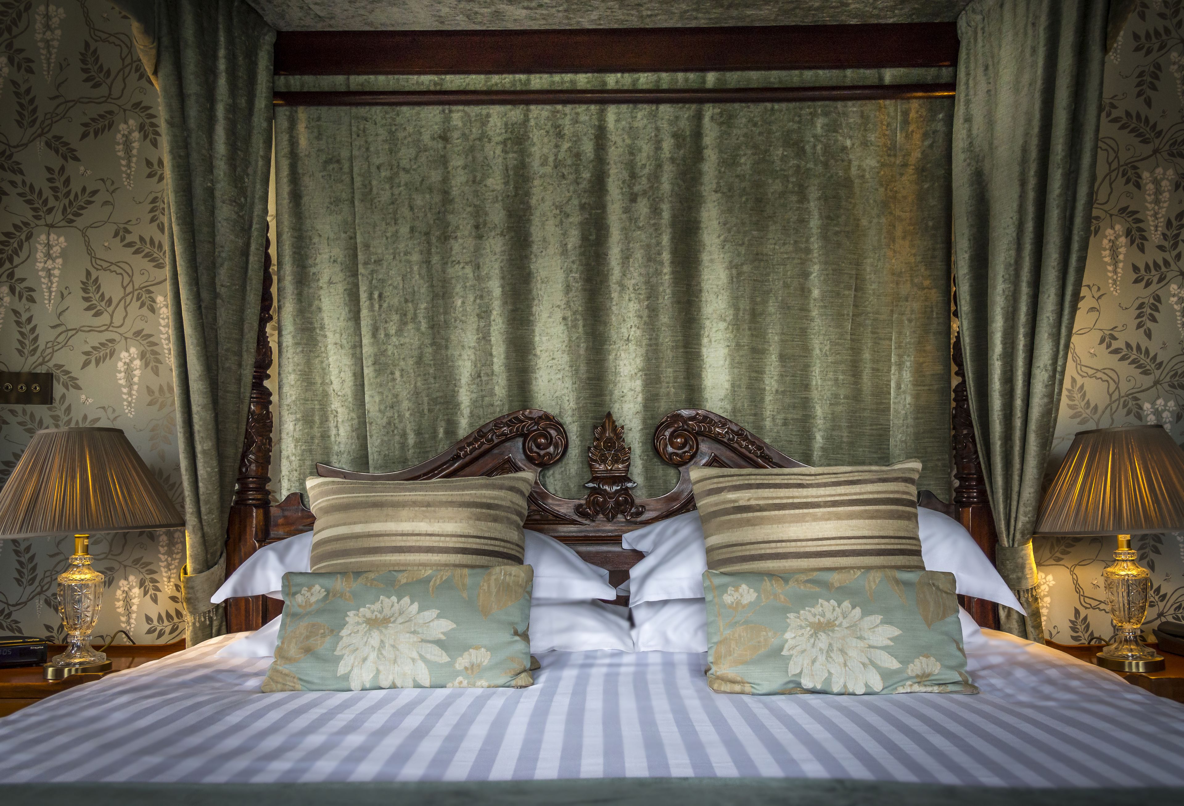A bed with striped bedding, two floral pillows, and a wooden headboard.