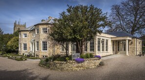 Un bâtiment historique en pierre, doté d’un espace d’accueil et d’un parking.