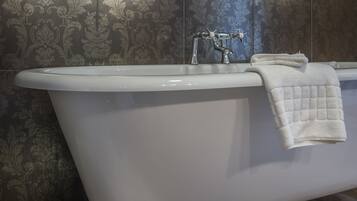 Una bañera independiente con una toalla blanca, azulejos decorativos en la pared y una base ornamental.