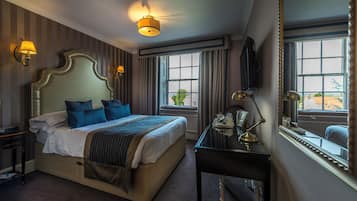 A hotel room with a large bed, bedside lamps, a desk with a mirror, and a window with curtains.