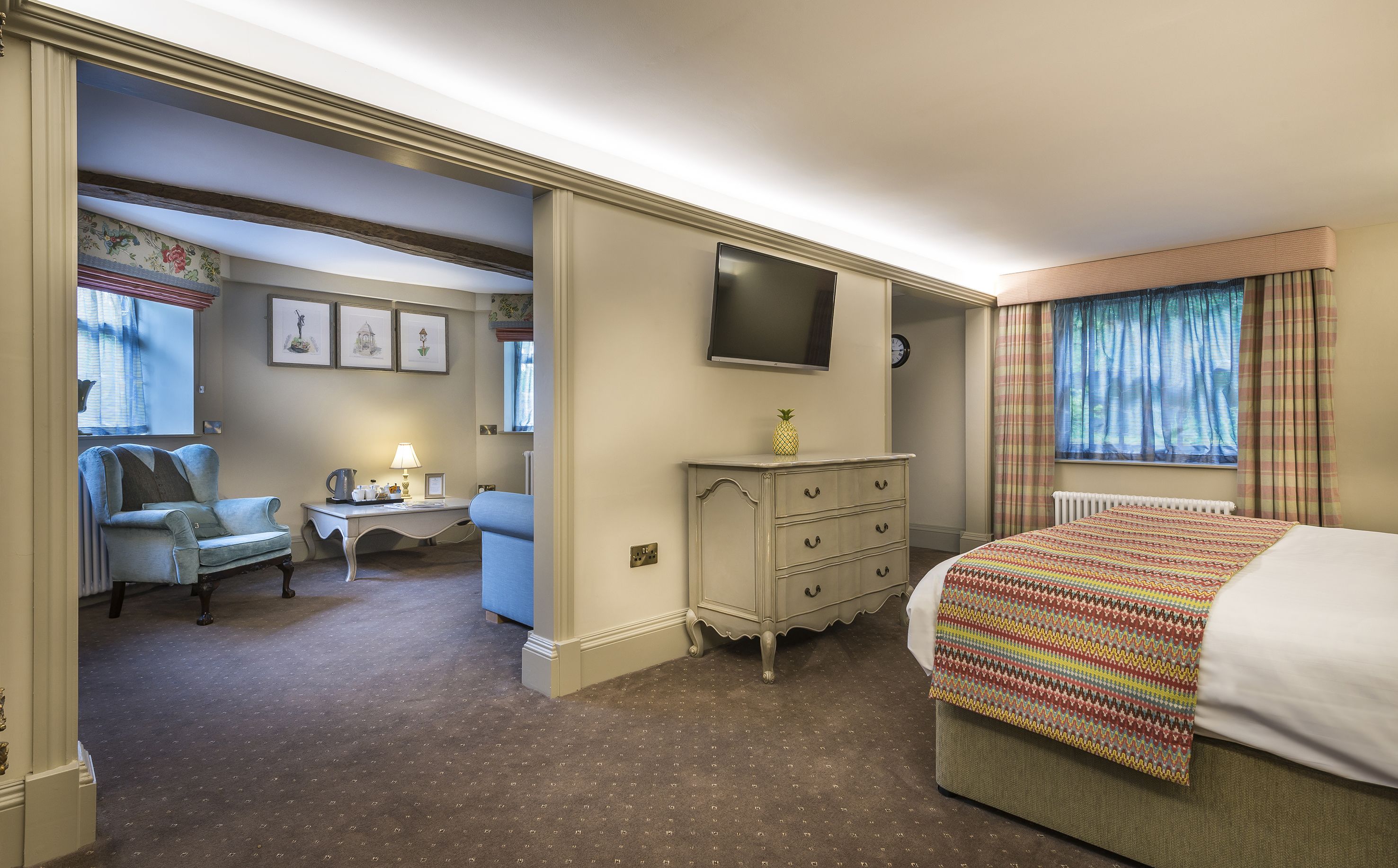 A hotel room with a bed, a desk with a chair, a dresser, and a television on the wall.