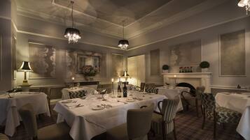 A formal dining room with multiple tables set for service, elegant chandeliers, and classic wall decor.