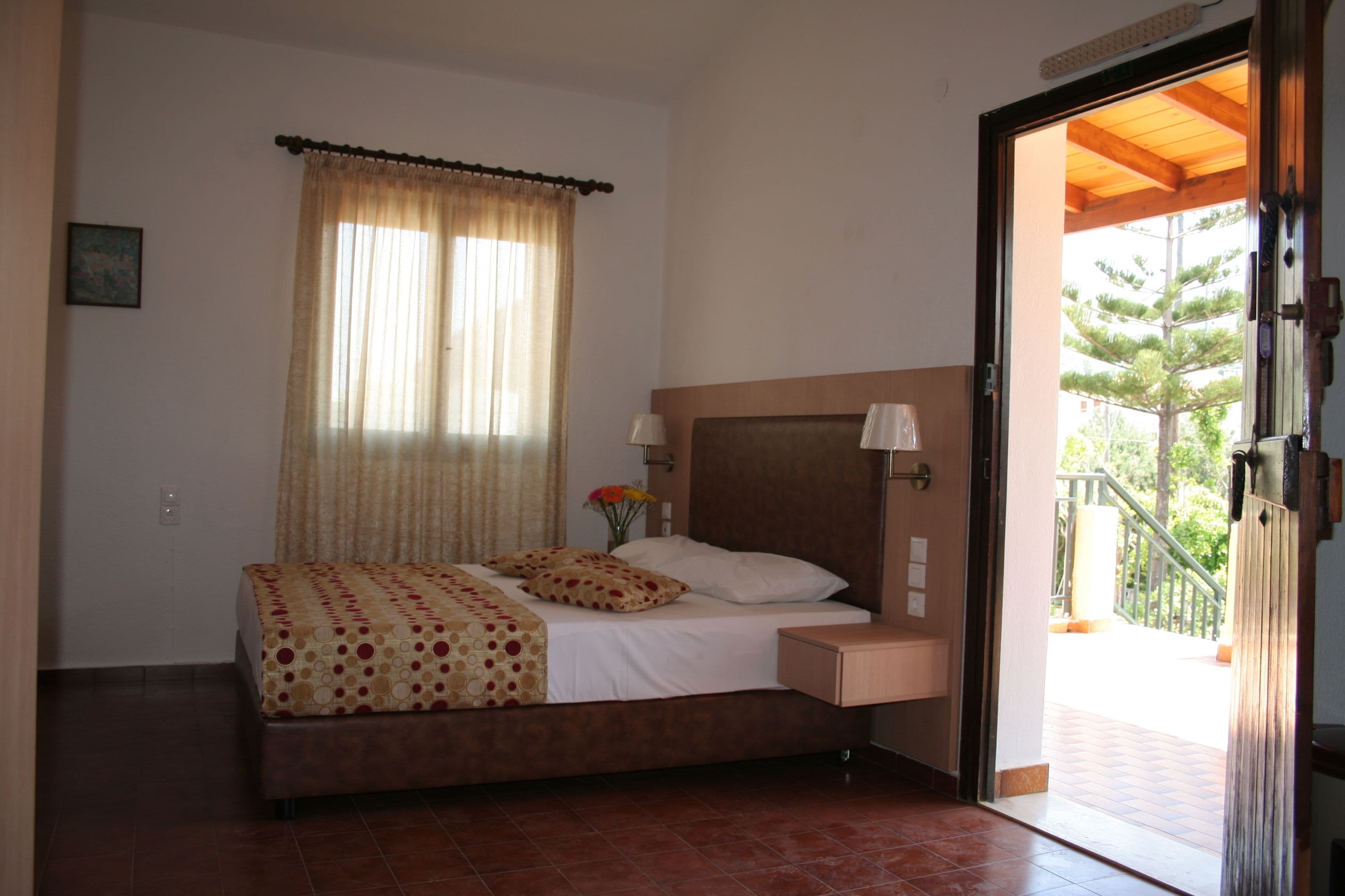 A bedroom with a bed, a nightstand, a lamp, and a window with curtains.