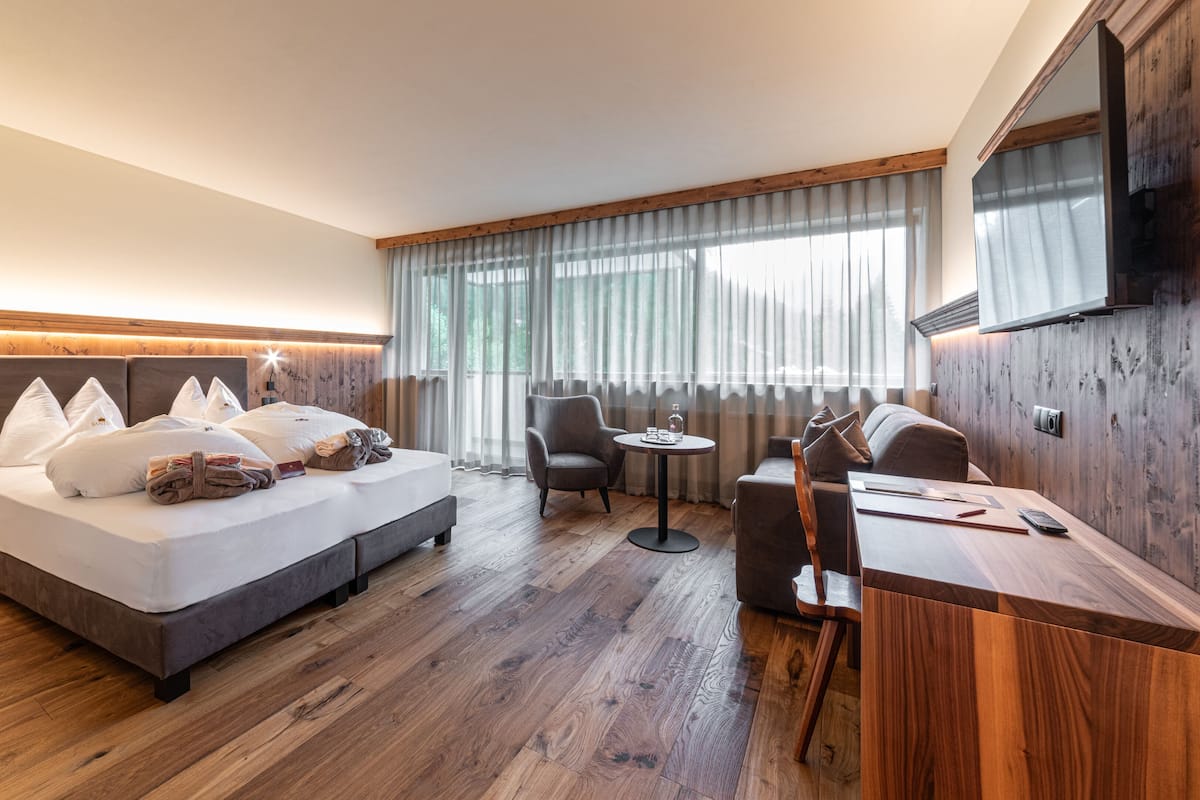 A hotel room with a large bed, a desk, a chair, and a TV.
