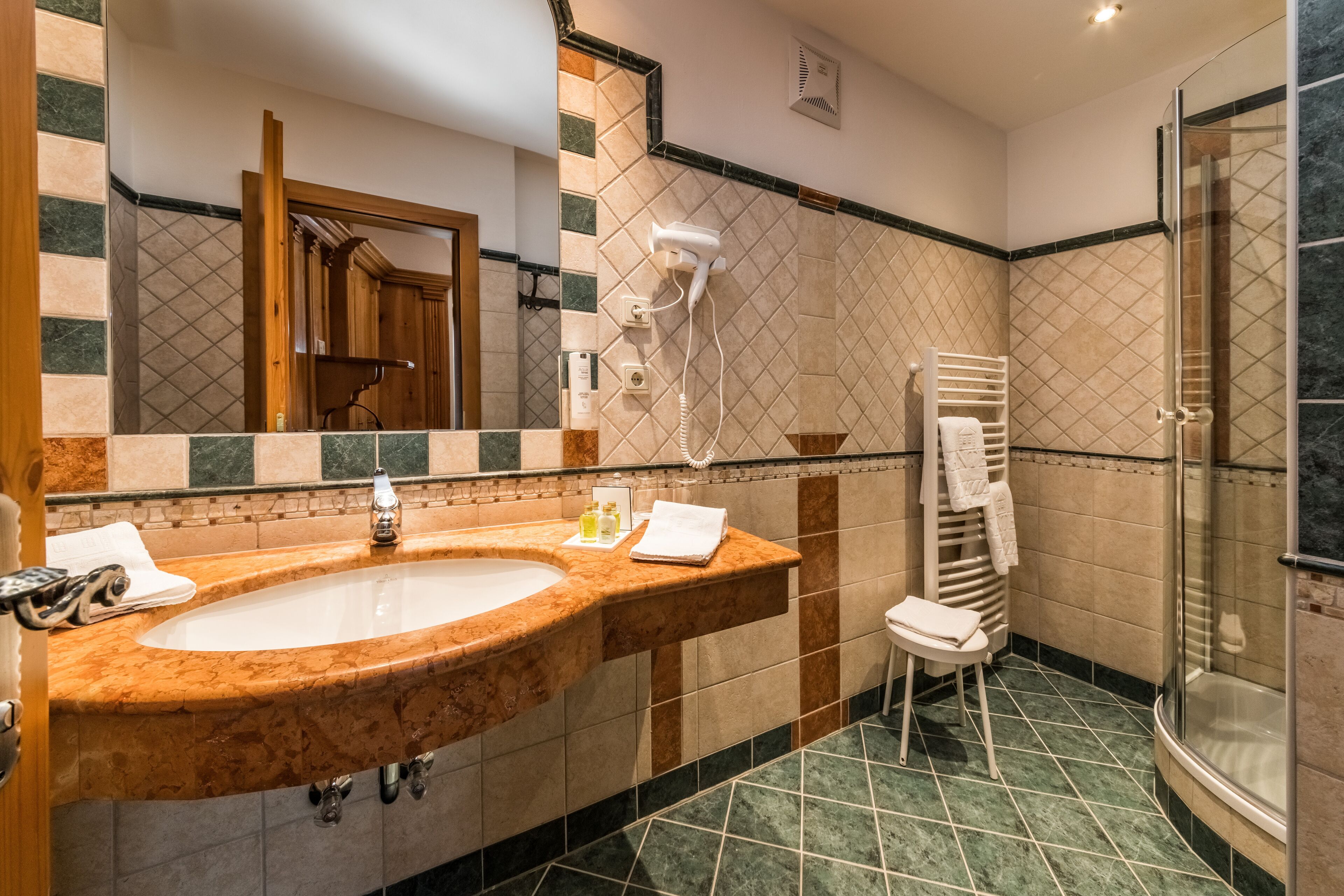 A bathroom with a large oval sink, a glass shower enclosure, and a towel rack.