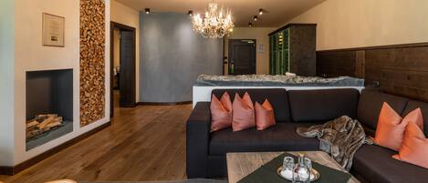 Un salón moderno con un sofá oscuro, una mesa de centro de madera y una araña.