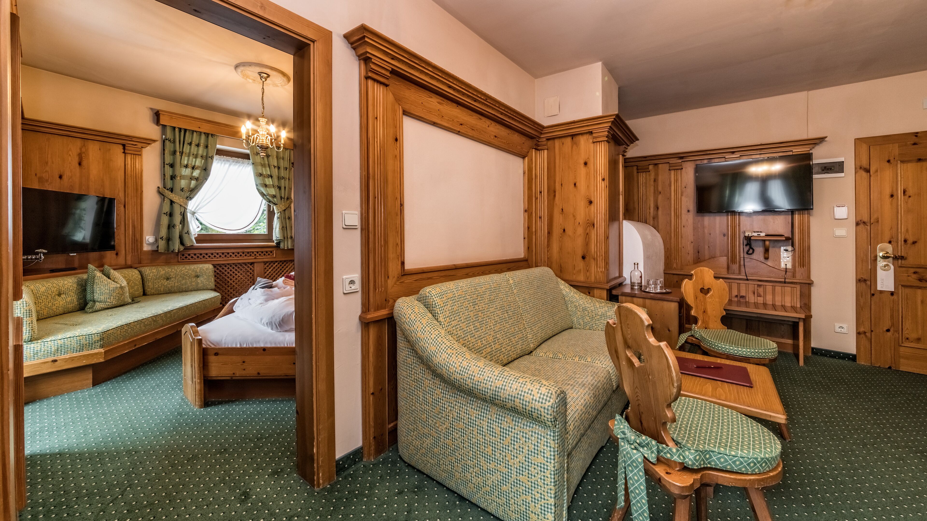 Ein gemütliches Zimmer mit einer Holzsofa, einem Bett, einem Holzstuhl und einem Fernseher.