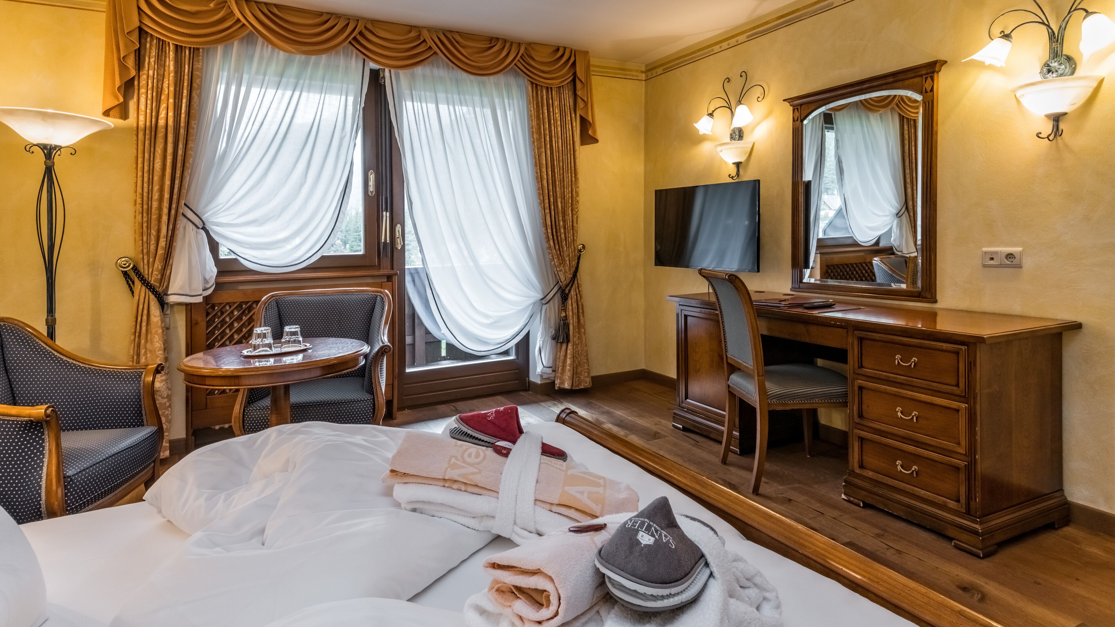 Una camera d'albergo con un letto, una scrivania, una sedia, un comodino e una televisione.