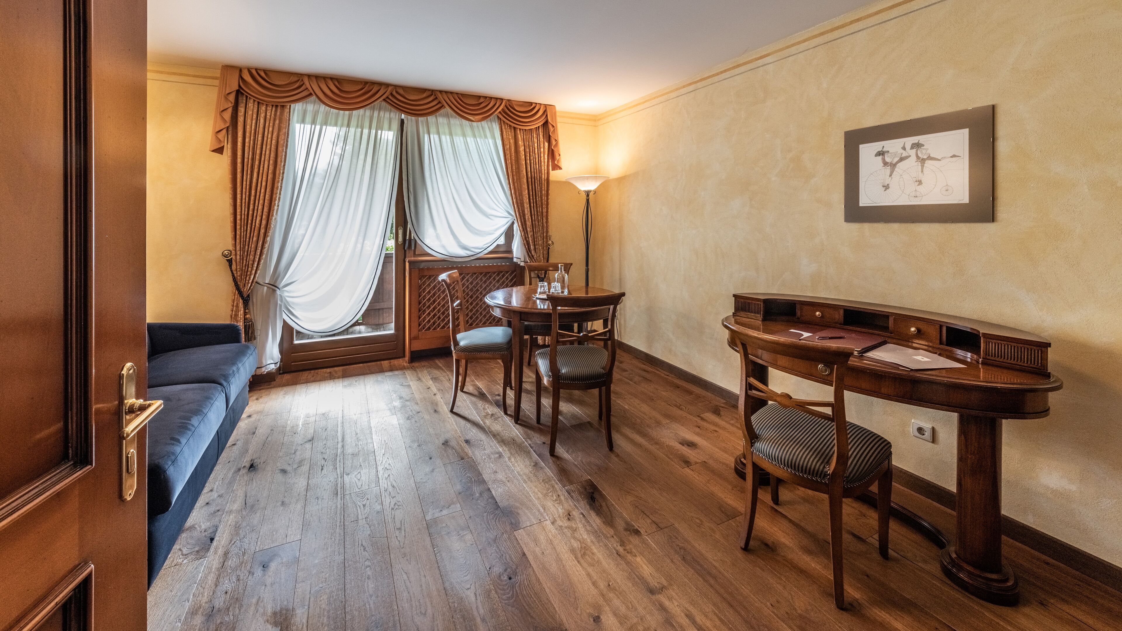 Une pièce avec un plancher en bois, un bureau avec une chaise, un canapé et une lampe.
