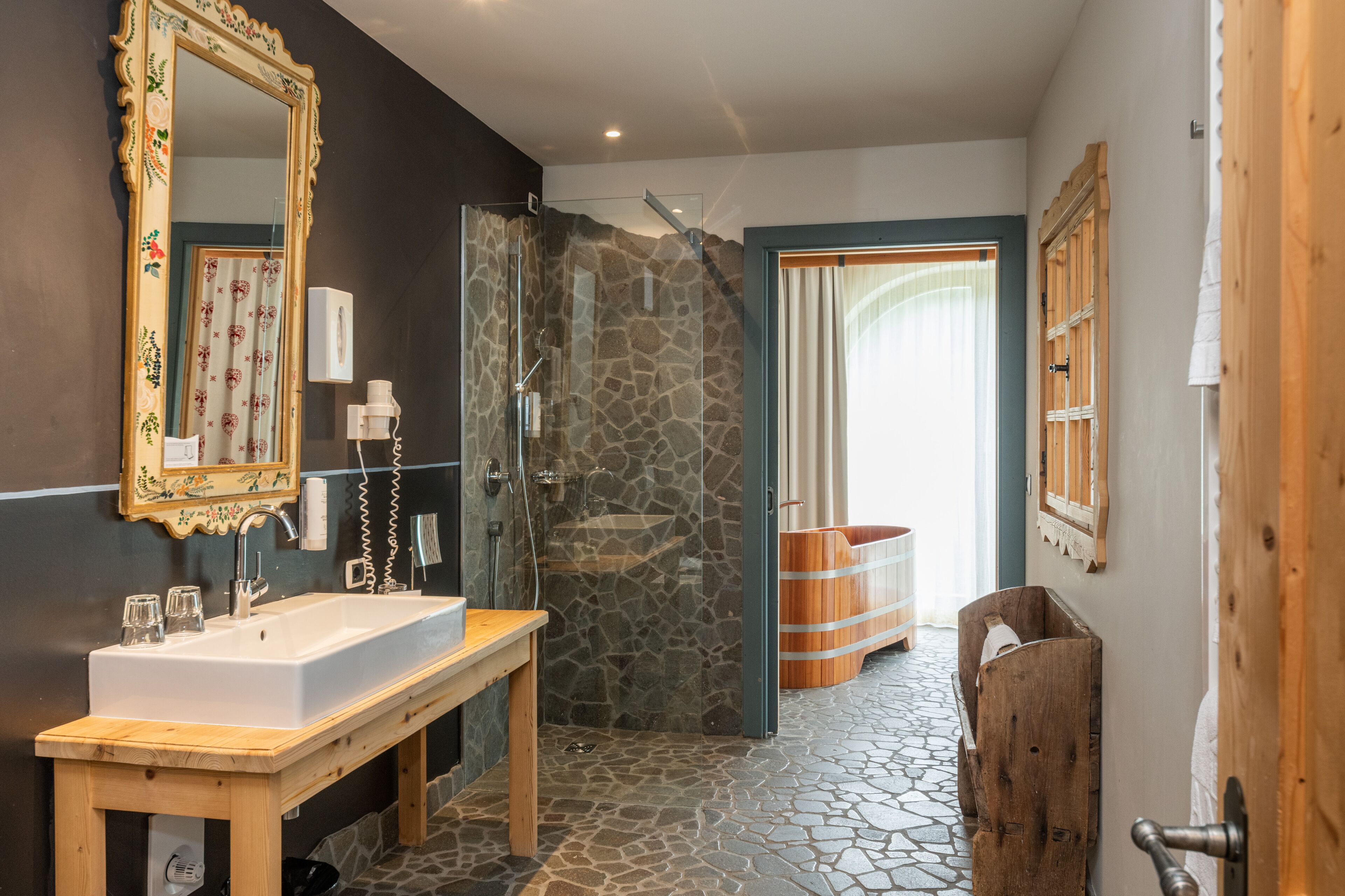 Une salle de bain avec une douche en pierre, un lavabo en bois et un grand miroir.