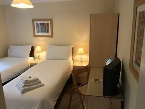 Una habitación de hotel con dos camas, un televisor y un cuadro en la pared.