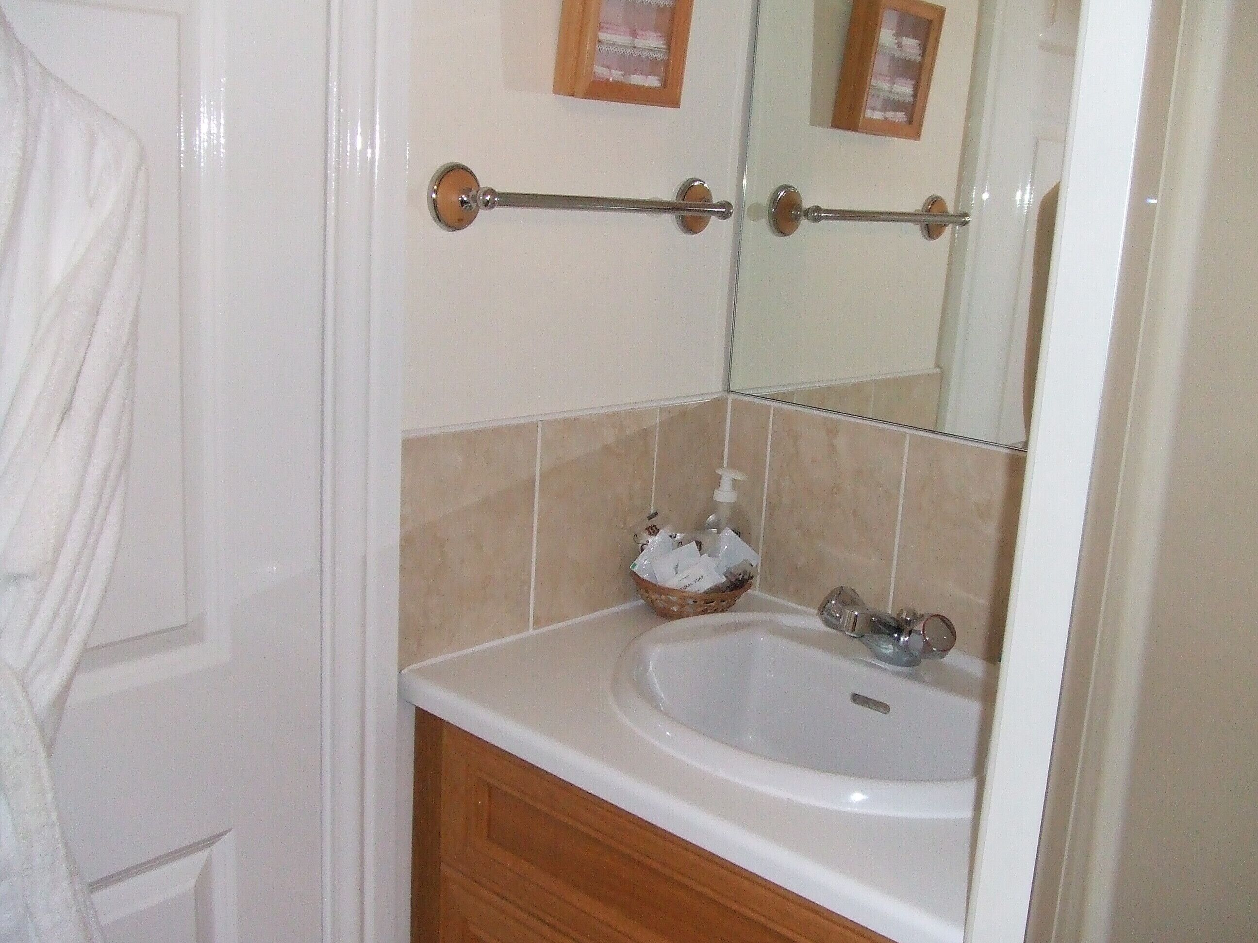 Une salle de bain avec un lavabo blanc, un meuble en bois et un porte-serviettes.