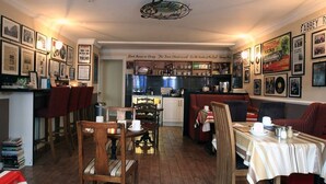 A cozy restaurant with wooden furniture, a kitchen in the center, and walls adorned with framed pictures and posters. - Abbey Bed and Breakfast (Londonderry)
