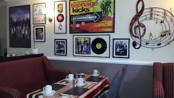 Una habitación con una pared decorada con carteles, un letrero que dice "Abbey Road" y una mesa servida con tazas y platillos.